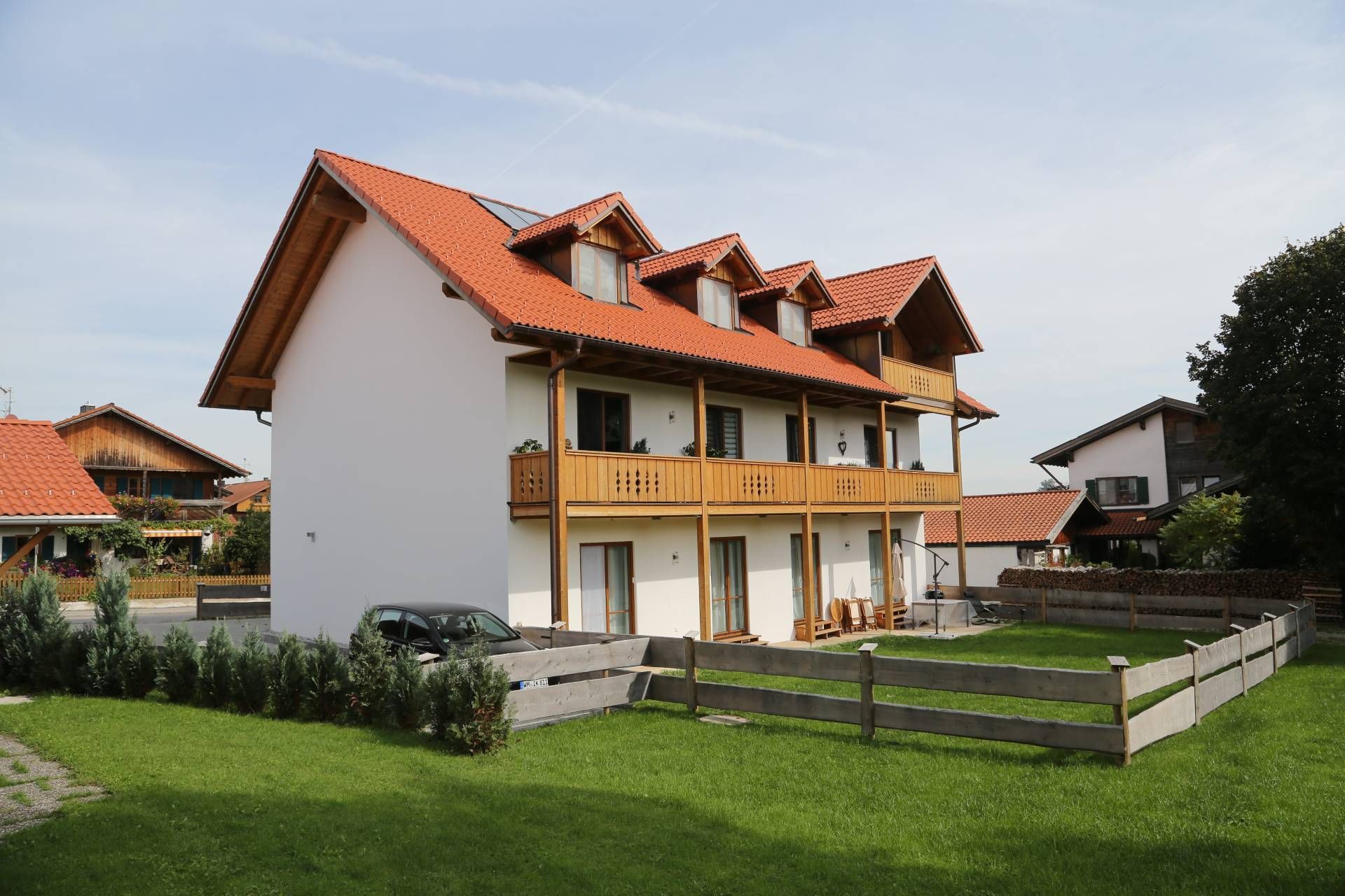 ein weißes Haus mit einem roten Dach und einem Holzzaun davor