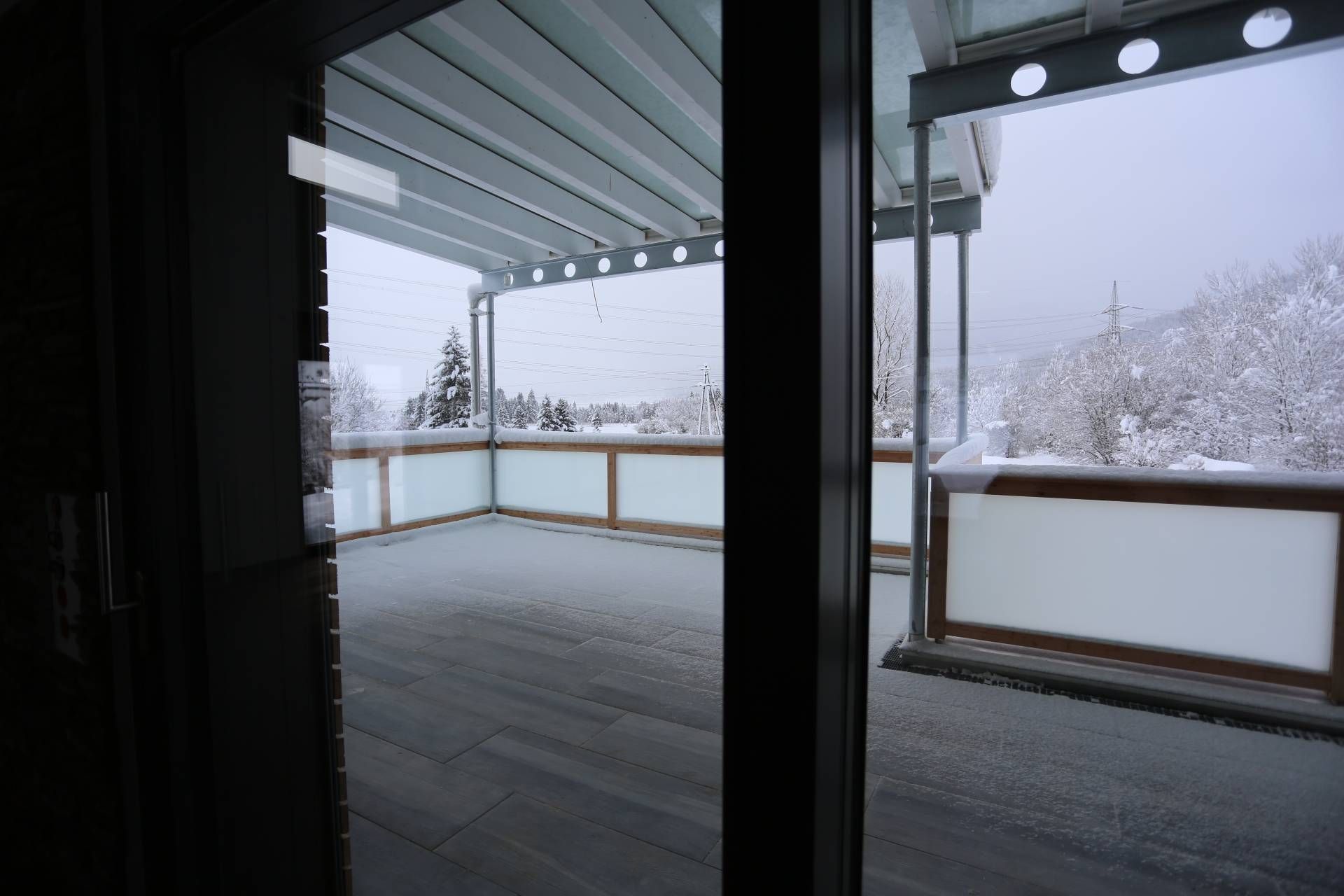 ein Balkon mit schneebedeckten Bäumen aus einem Fenster