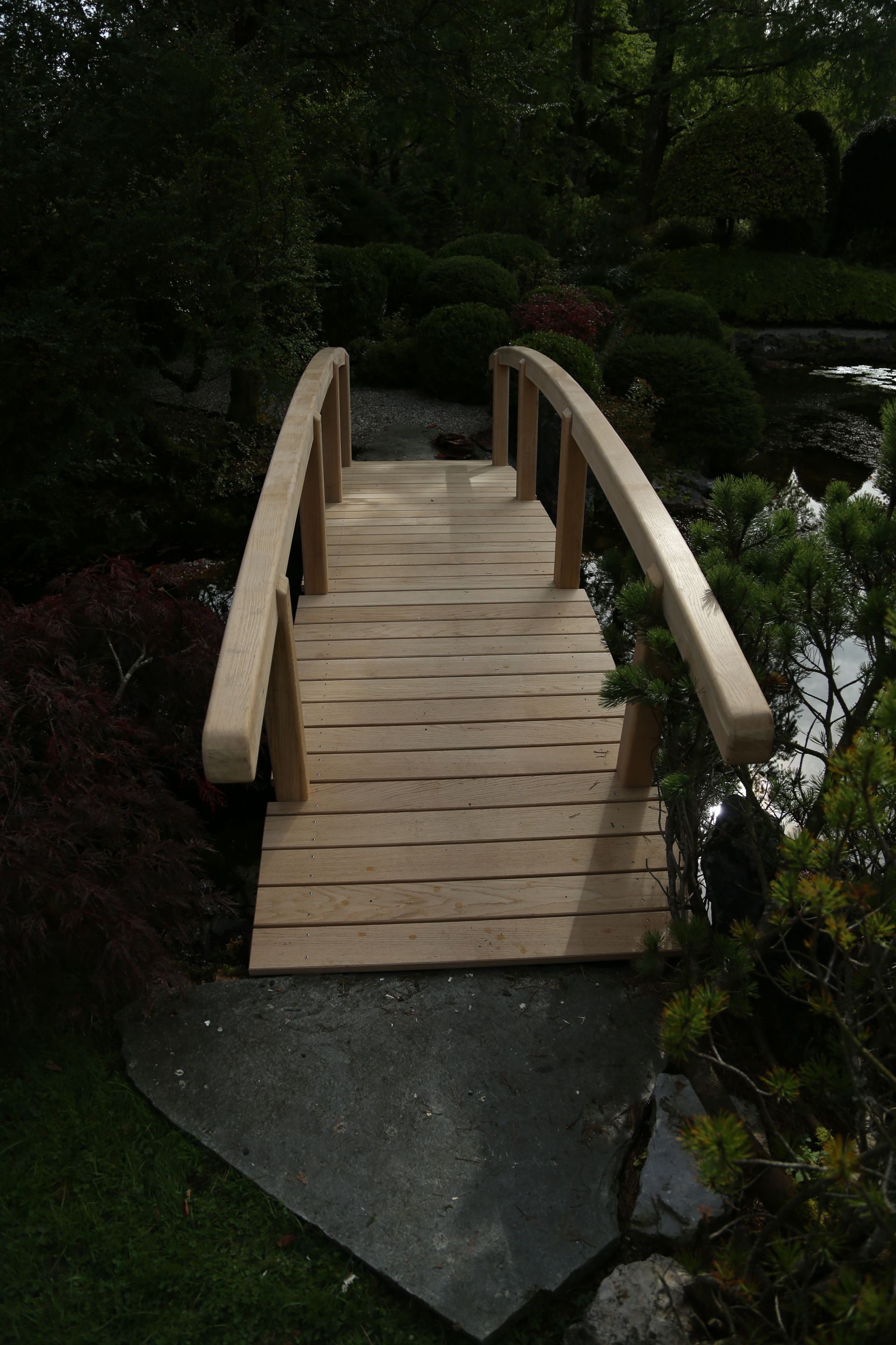 eine Holzbrücke über einen Teich in einem Garten