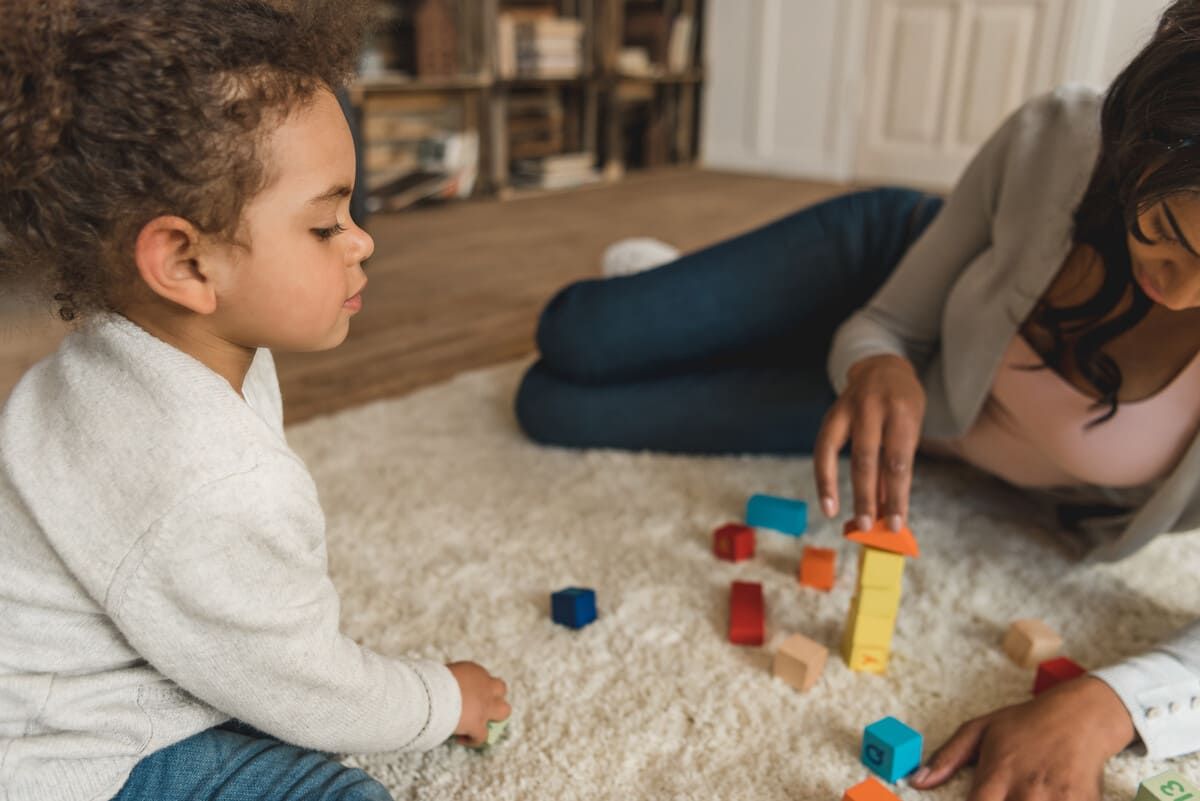 Una mujer y un niño están jugando con bloques de madera en el suelo.