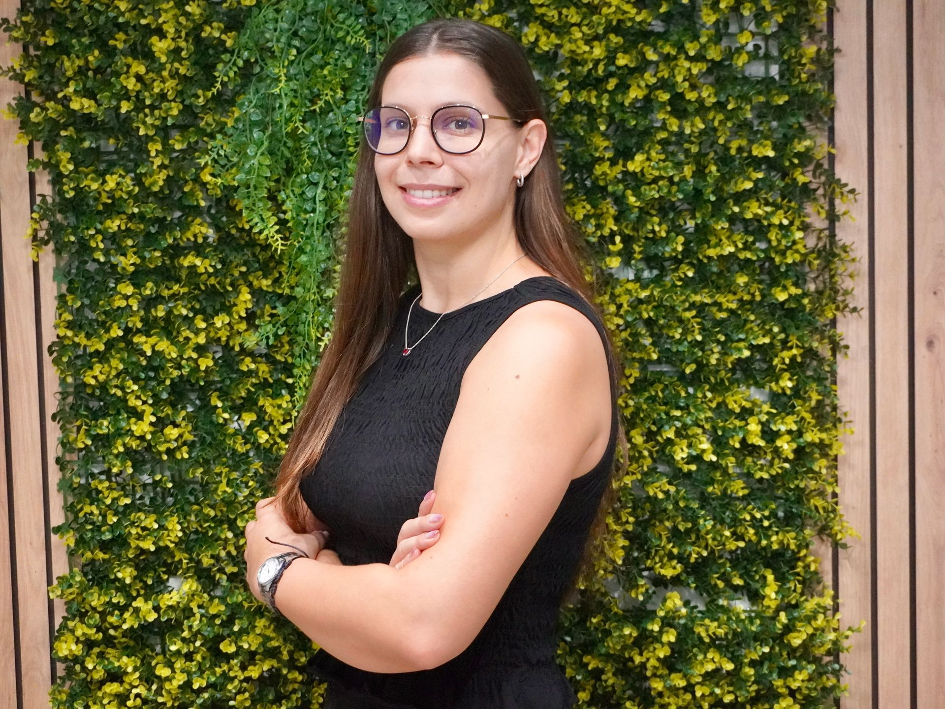 Una mujer con una chaqueta blanca y pantalones rosas está parada frente a una pared de vidrio.