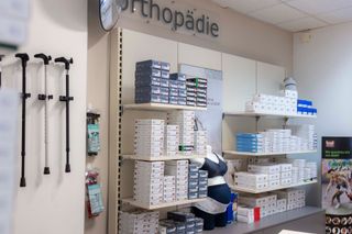 Orthopädische Produkte werden in den Regalen eines Ladens ausgestellt; links Gehstöcke, Pakete und Schachteln.