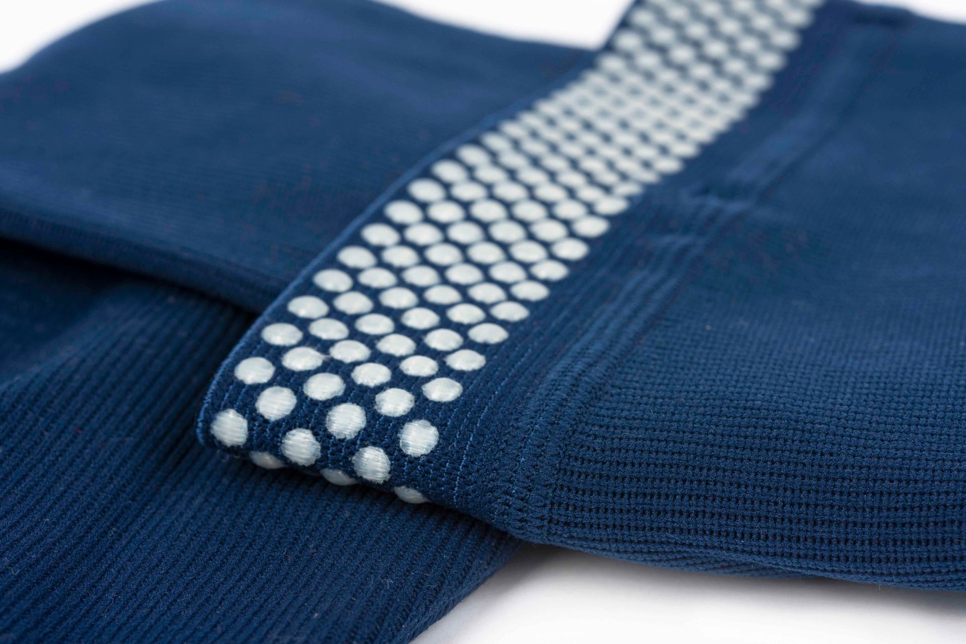 Nahaufnahme von blauen Socken mit weißen Anti-Rutsch-Noppen am Bündchen.
