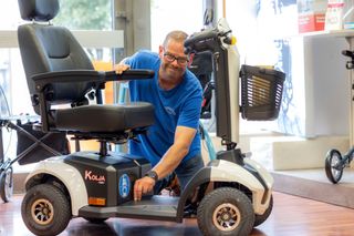 Mann im blauen Hemd passt einen weißen Elektromobil an. Inneneinstellung.