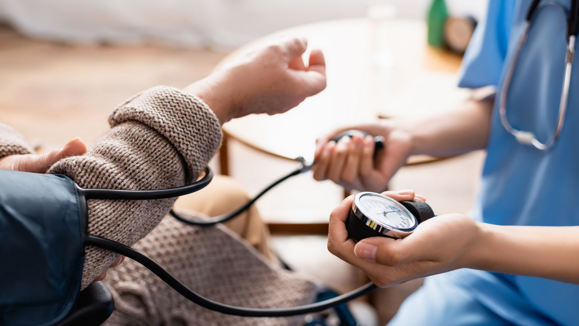 Le bras d'une personne est mesuré pour déterminer sa tension artérielle par un professionnel de la santé portant une tenue bleue.