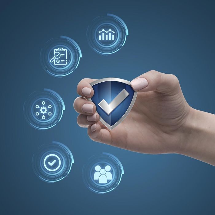 Mano sosteniendo un escudo azul con una marca de verificación, rodeado de iconos de seguridad brillantes sobre un fondo azul.
