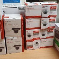 Pinoittain laatikoituja turvakameroita kaupan hyllyllä, enimmäkseen valkoisia ja oransseja pakkauksia.