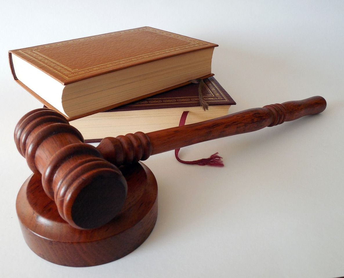 Un maillet de juge en bois posé sur son socle rond à côté d'un livre fermé