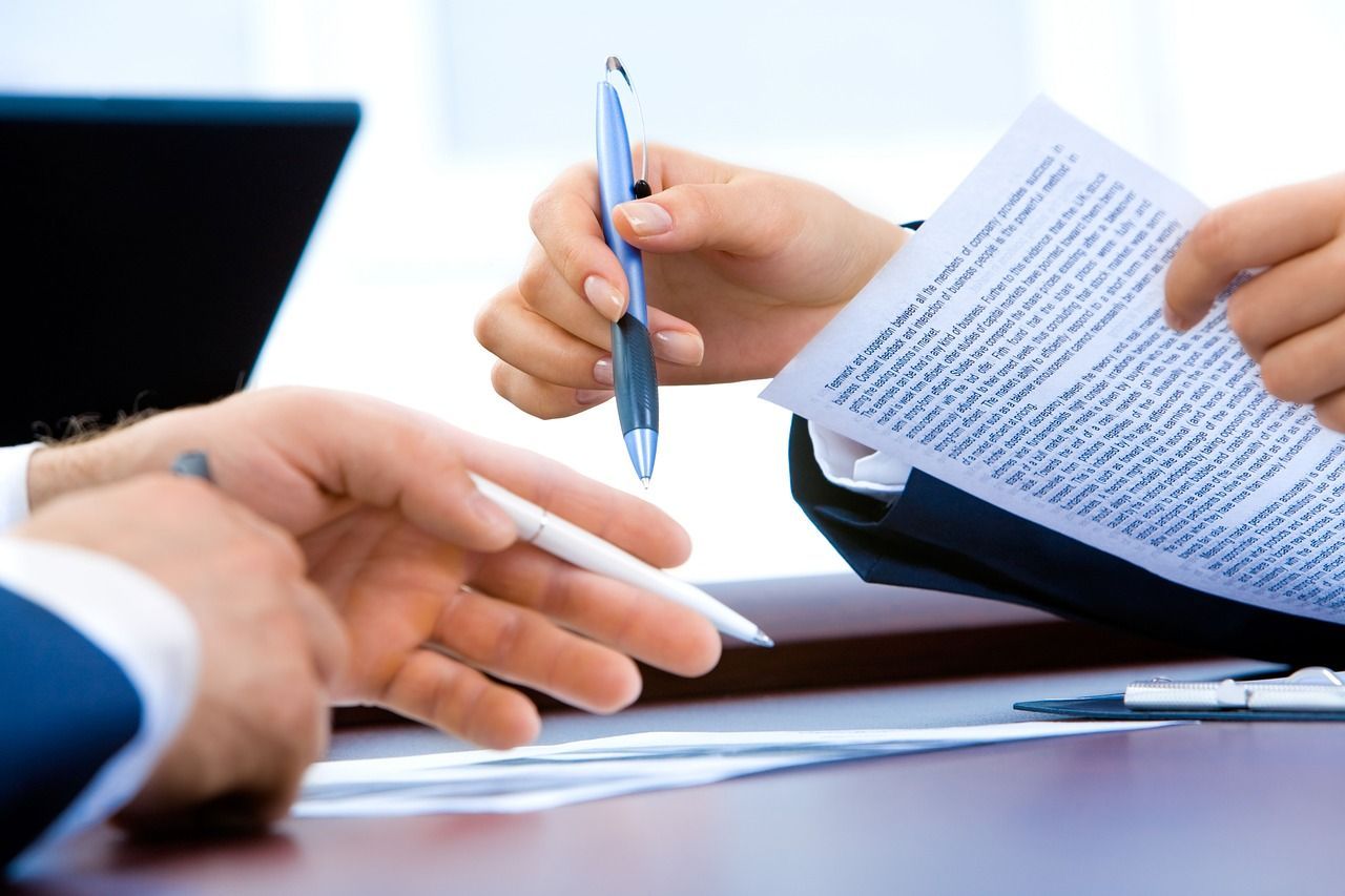 Des mains échangeant un stylo et des documents lors d'une réunion d'affaires à un bureau