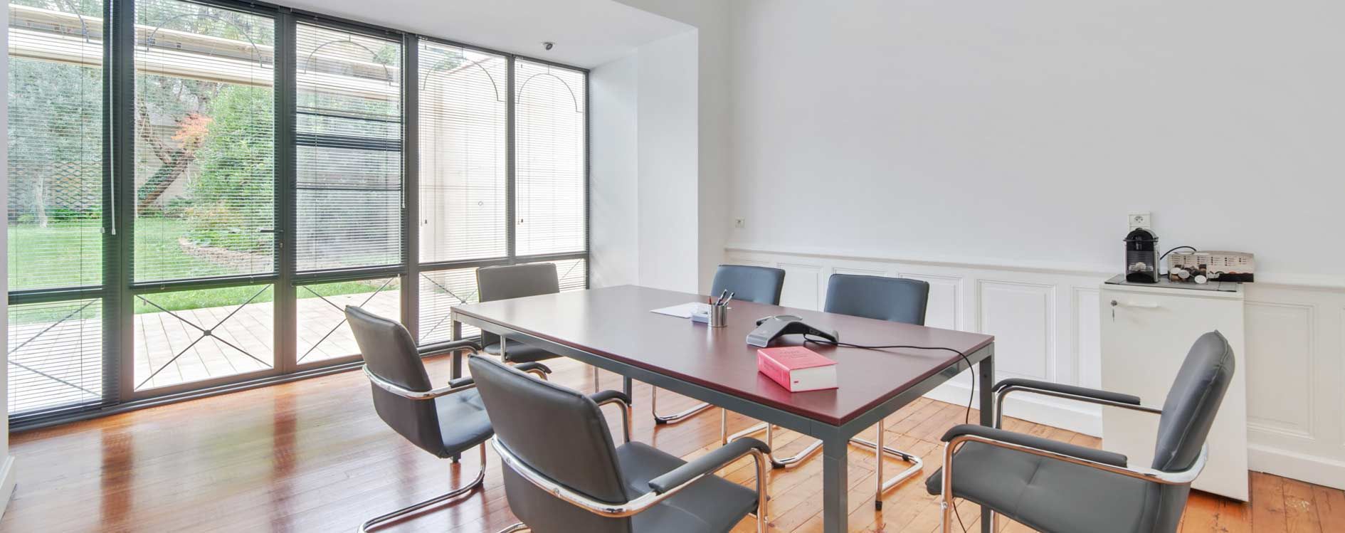 Salle à manger moderne avec une table en verre, des chaises grises et de grandes portes coulissantes donnant sur une terrasse