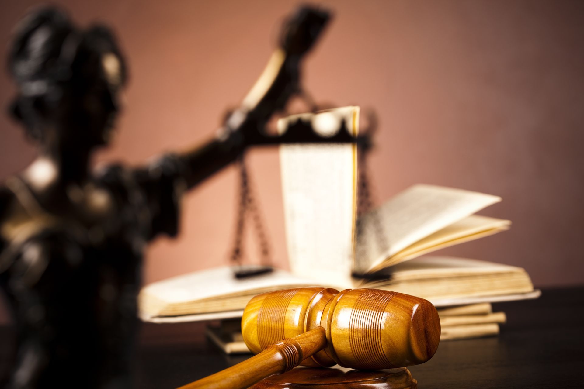Le marteau d'un juge posé sur son bureau, avec des livres de droit et une balance de la justice floue en arrière-plan.