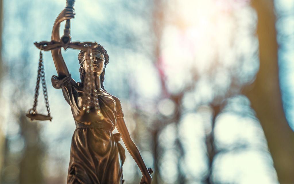 Statue de la Justice en bronze tenant une balance, arrière-plan légèrement flou