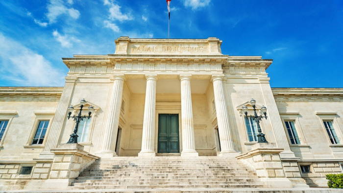 Grand bâtiment néoclassique en pierre avec de hautes colonnes et un ciel d'un bleu éclatant