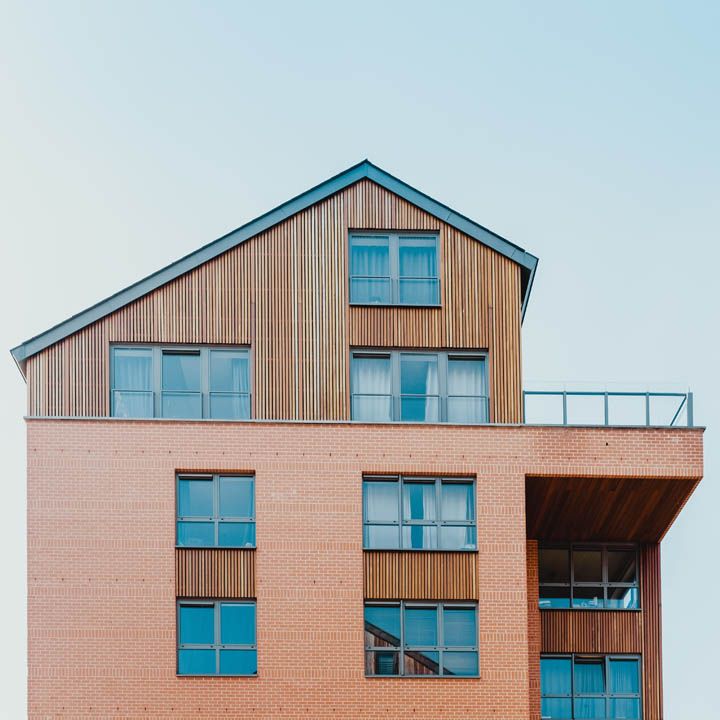 Immeuble d'appartements moderne avec façade en briques et en bois se détachant sur un ciel dégagé