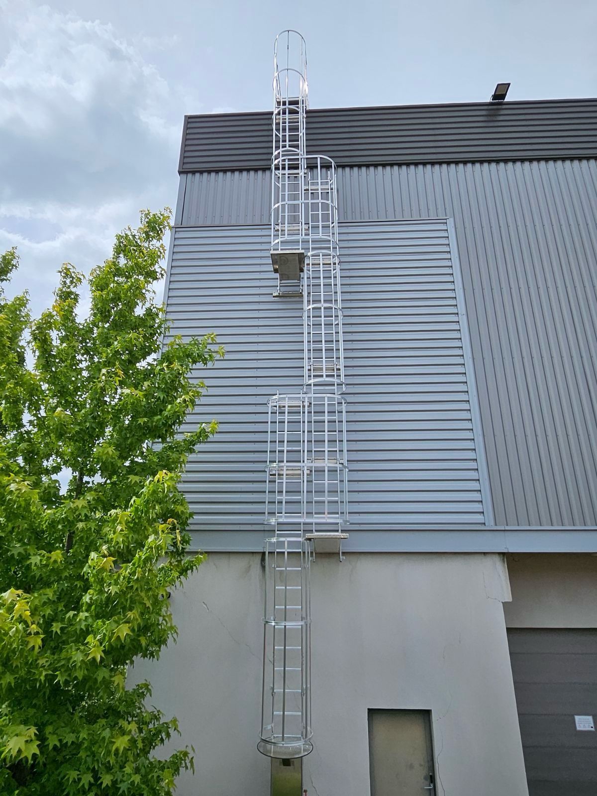 Échelle à crinoline sur un bâtiment gris.