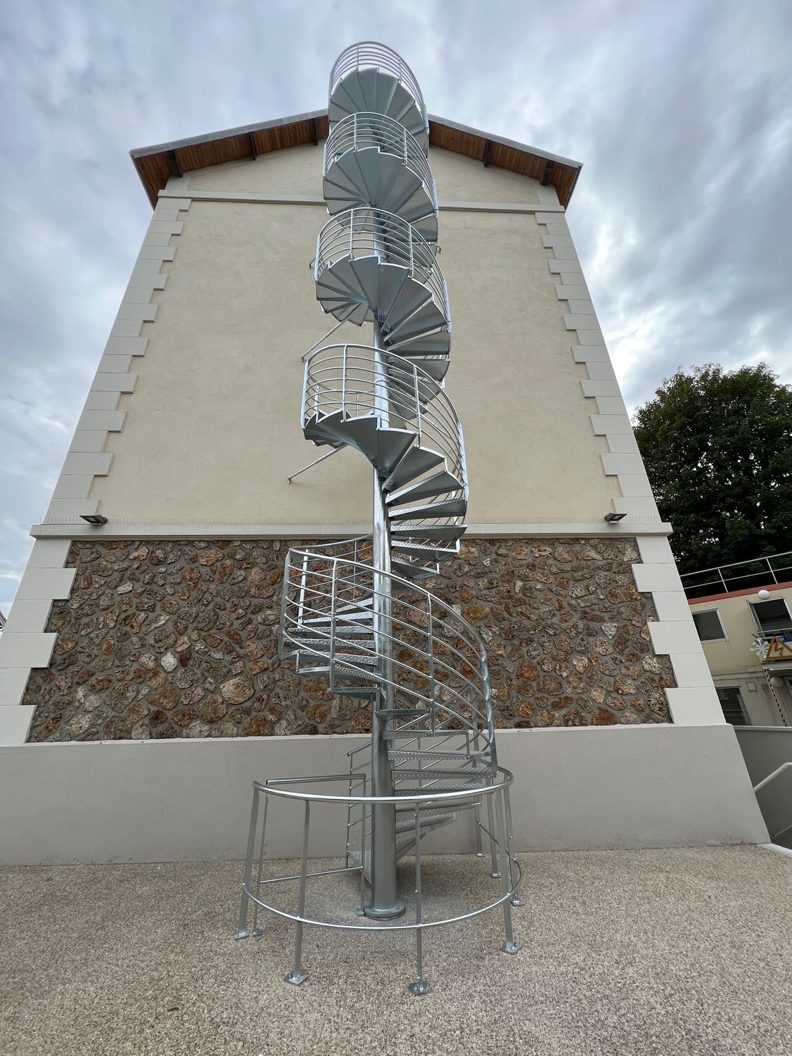 Un escalier de secours en colimaçon de couleur argentée.