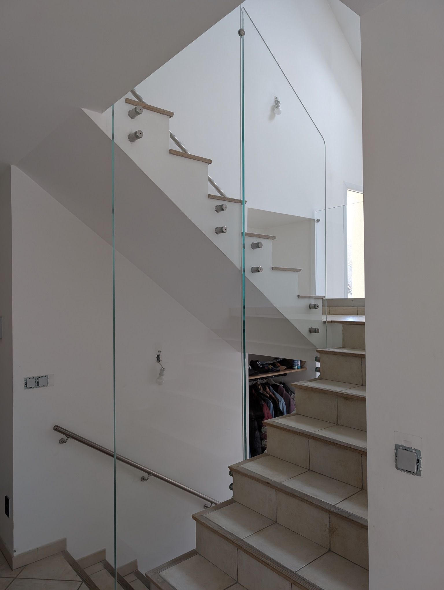 Un escalier intérieur avec des garde-corps transparents.