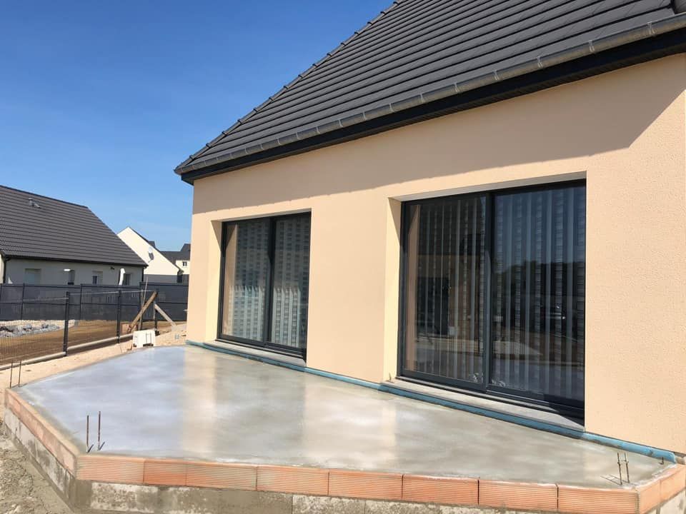 Patio de maison moderne avec de grandes portes coulissantes en verre et une terrasse couverte en béton