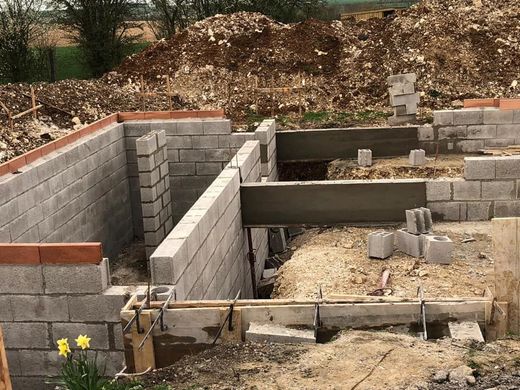 Fondations en parpaings partiellement construites avec coffrages en bois sur un chantier de construction