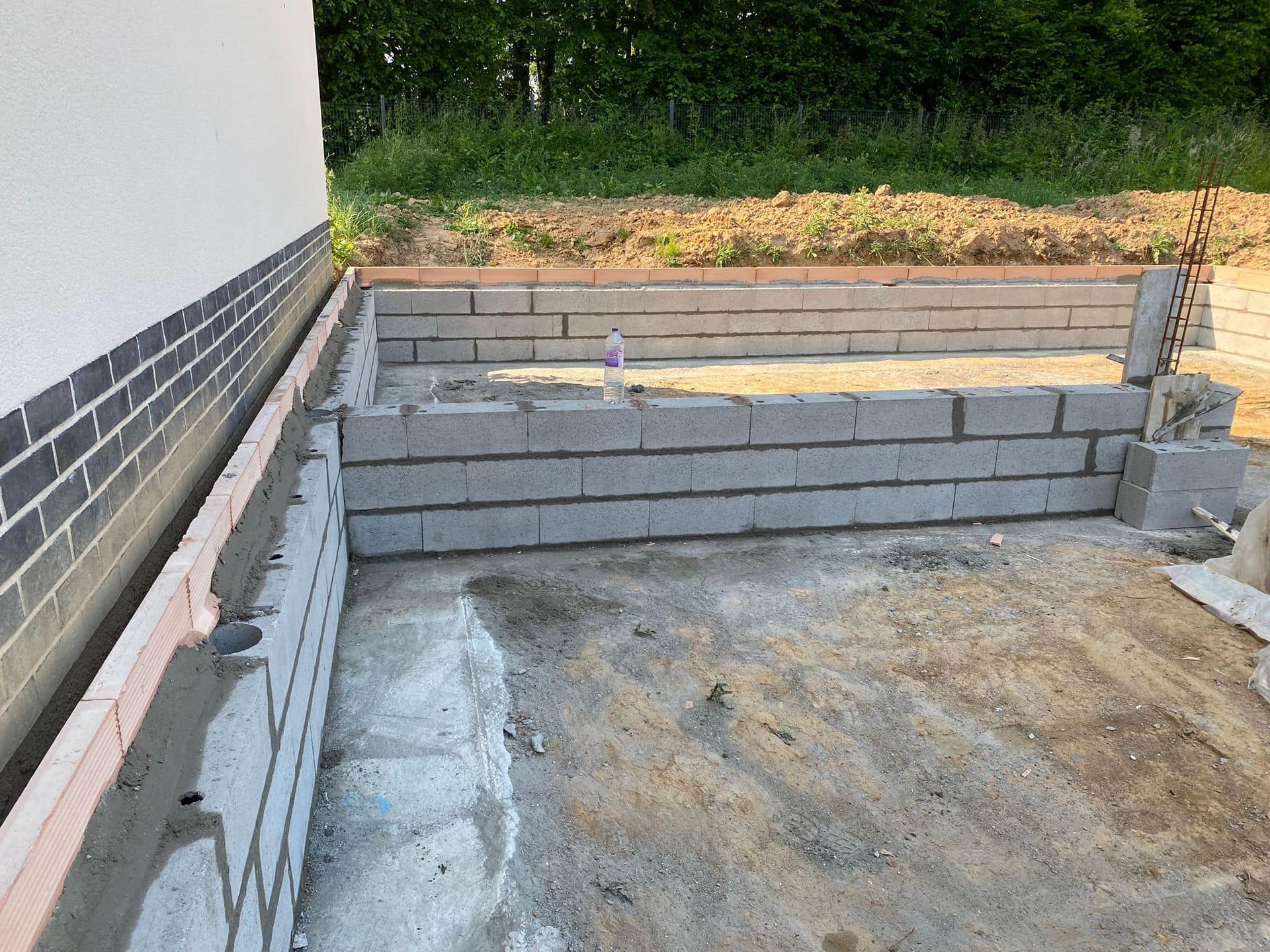 Des marches en béton sont en construction à côté d'une maison, menant à une cour gazonnée.