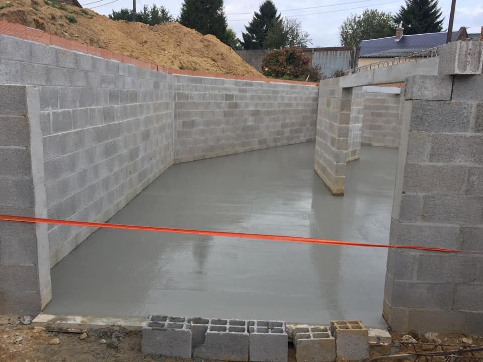 Fondations de sous-sol en béton en construction avec murs en parpaings et dalle de sol neuve.