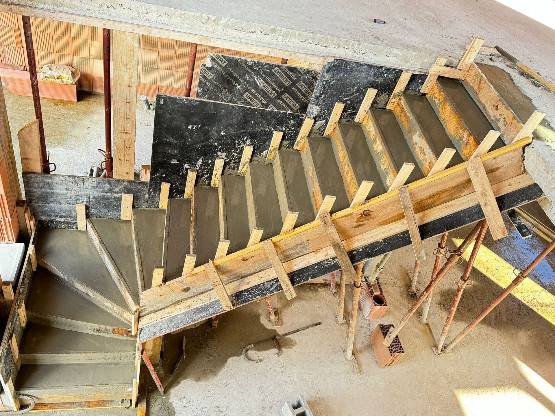 Escalier en bois en construction à l'intérieur d'une maison, avec charpente apparente et marches installées