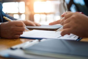 Una persona está escribiendo en un trozo de papel con un bolígrafo.