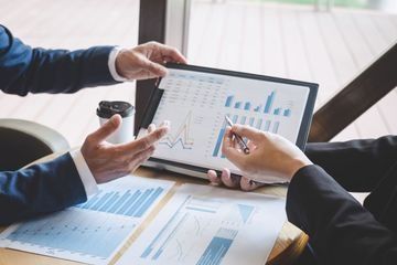 Dos personas están sentadas en una mesa mirando una computadora portátil.