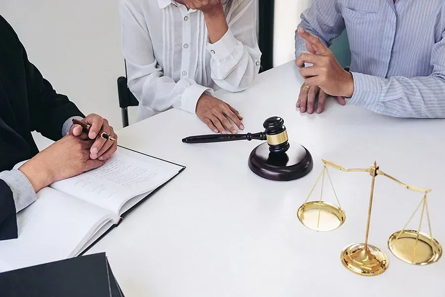 Un grupo de personas está sentado en una mesa con un mazo y una balanza de la justicia.