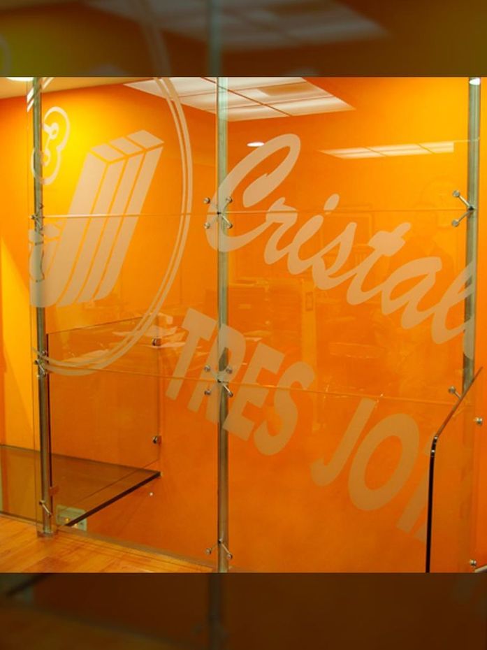 Habitación con paredes de color naranja, estantes de vidrio y logotipo blanco grabado y texto 