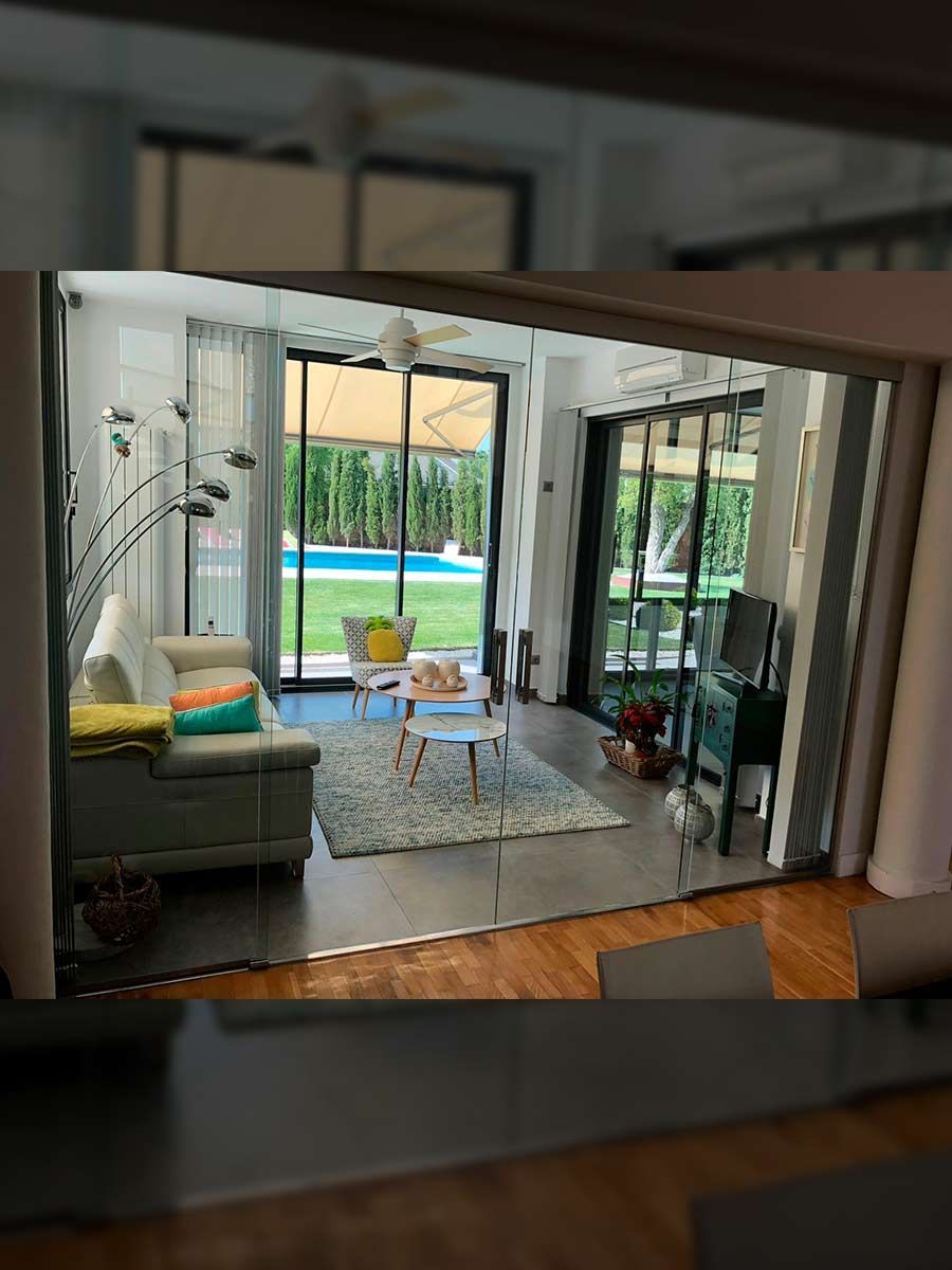 Sala de estar reflejada en un espejo, con vista a una piscina y un patio.