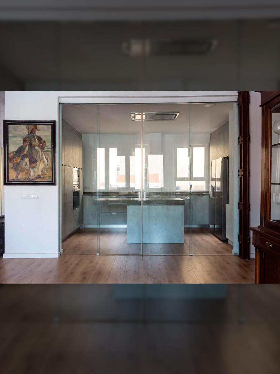 Una cocina moderna con puertas de vidrio, una isla gris y piso de madera.