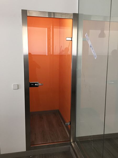 Puertas de vidrio con marco de acero inoxidable y franja horizontal esmerilada.