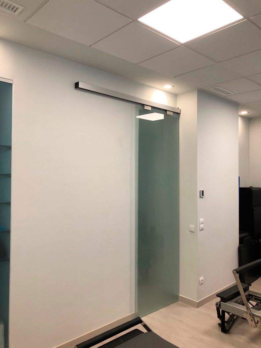 Puertas automáticas de cristal, paredes rojas y un cubo de basura de acero inoxidable en el interior.