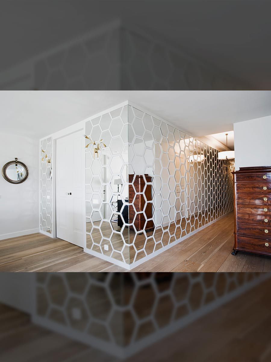 Un espejo grande y rectangular con iluminación LED, montado en una pared rayada sobre un mostrador blanco con decoración.