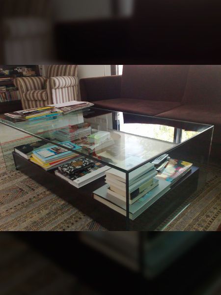 Mesa con tapa de cristal y patas de madera en una habitación con paredes moradas y suelo de madera oscura.