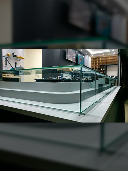 Vitrina de cristal con interior escalonado, base negra, en tienda.