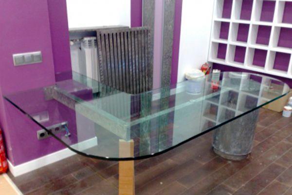 Mesa de cristal en una habitación con paredes violetas, un calefactor alto y suelo de madera.