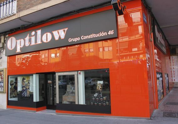 Fachada de tienda Optilow Grupo Constitución 46 con fachada, escaparates y señalización en color naranja.