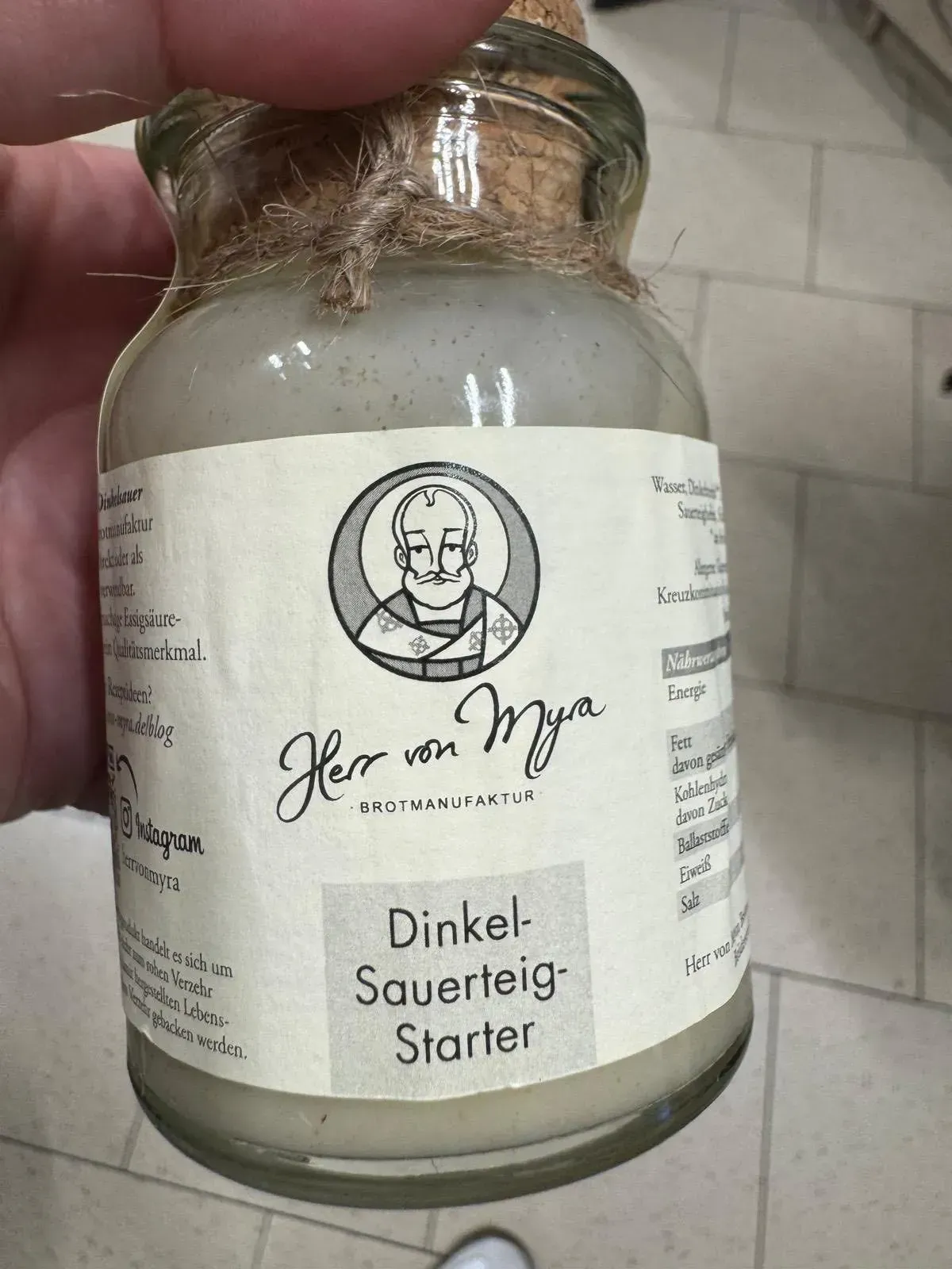 Glas mit Roggen-Sauerteig-Starter. Weißes Etikett mit der Zeichnung des Logos.