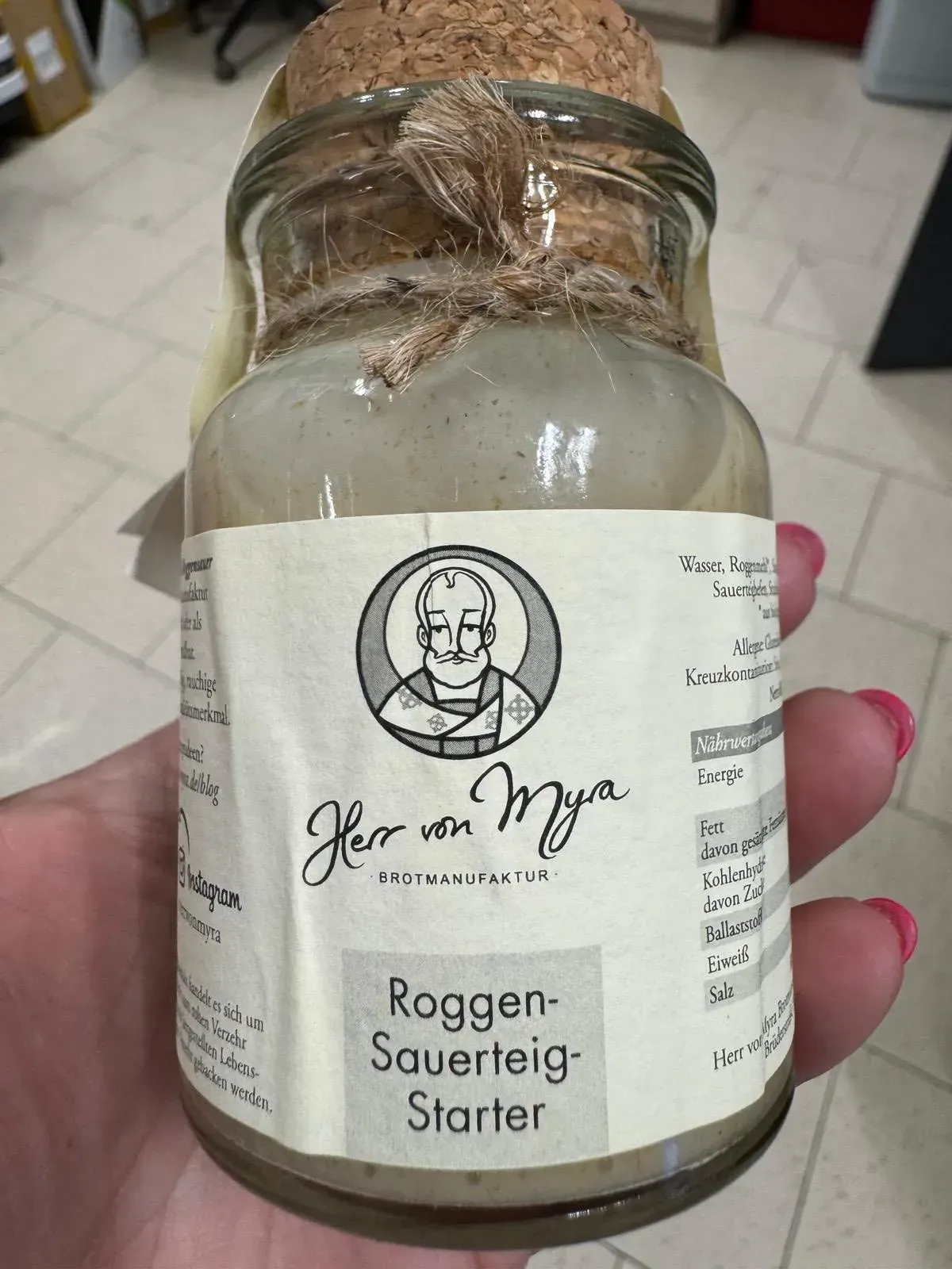 Glas mit Roggen-Sauerteig-Starter. Weißes Etikett mit der Zeichnung des Logos.
