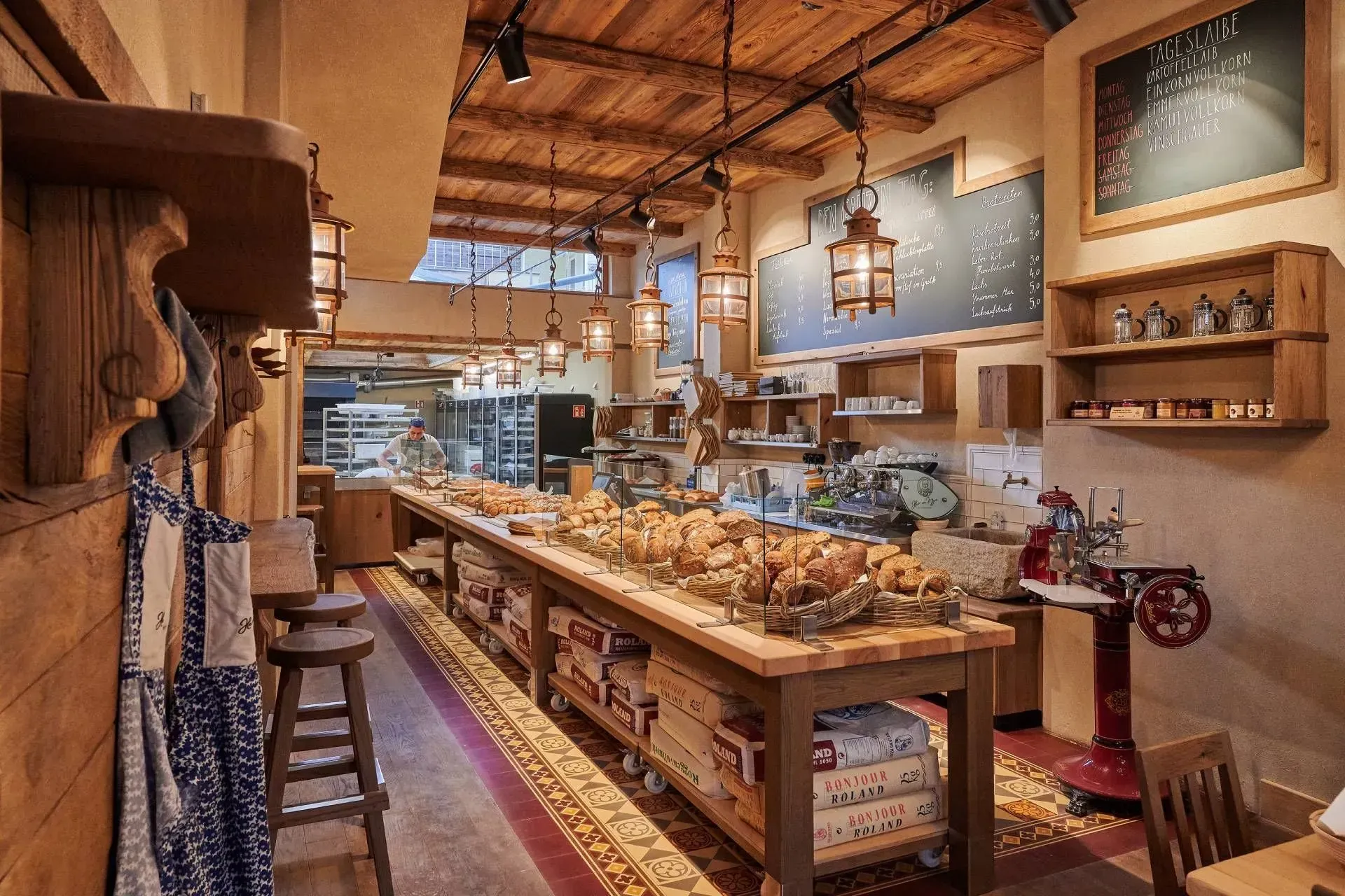 Interieur einer Bäckerei mit rustikaler Holzdekoration, auf einem langen Tisch werden Gebäckstücke präsentiert.