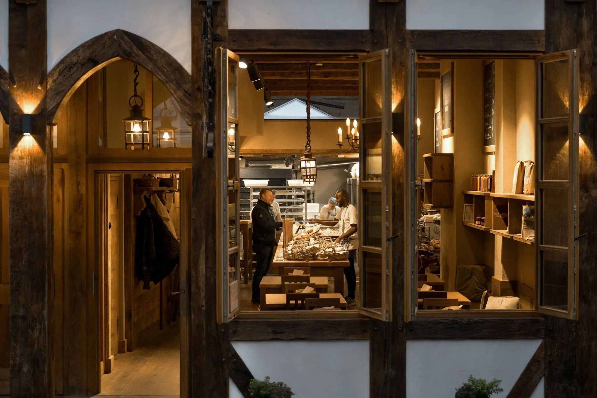 Ladeninterieur mit Holzbalken, Verkaufsregalen und Kunden beim Stöbern. Sanftes Licht setzt die Produkte in Szene.