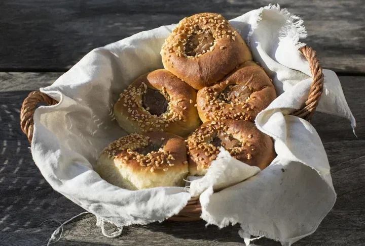 Ein Korb mit runden Backwaren mit Nussbelag, auf einem weißen Tuch.
