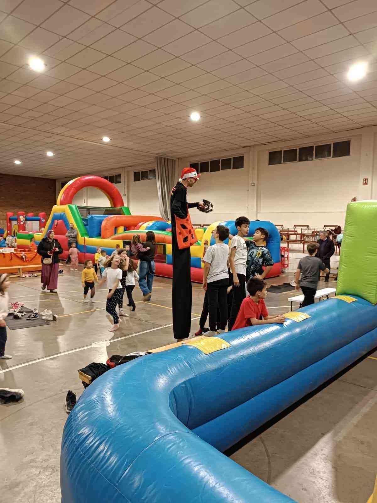 Circuito de obstáculos inflable interior con niños jugando en un gimnasio.