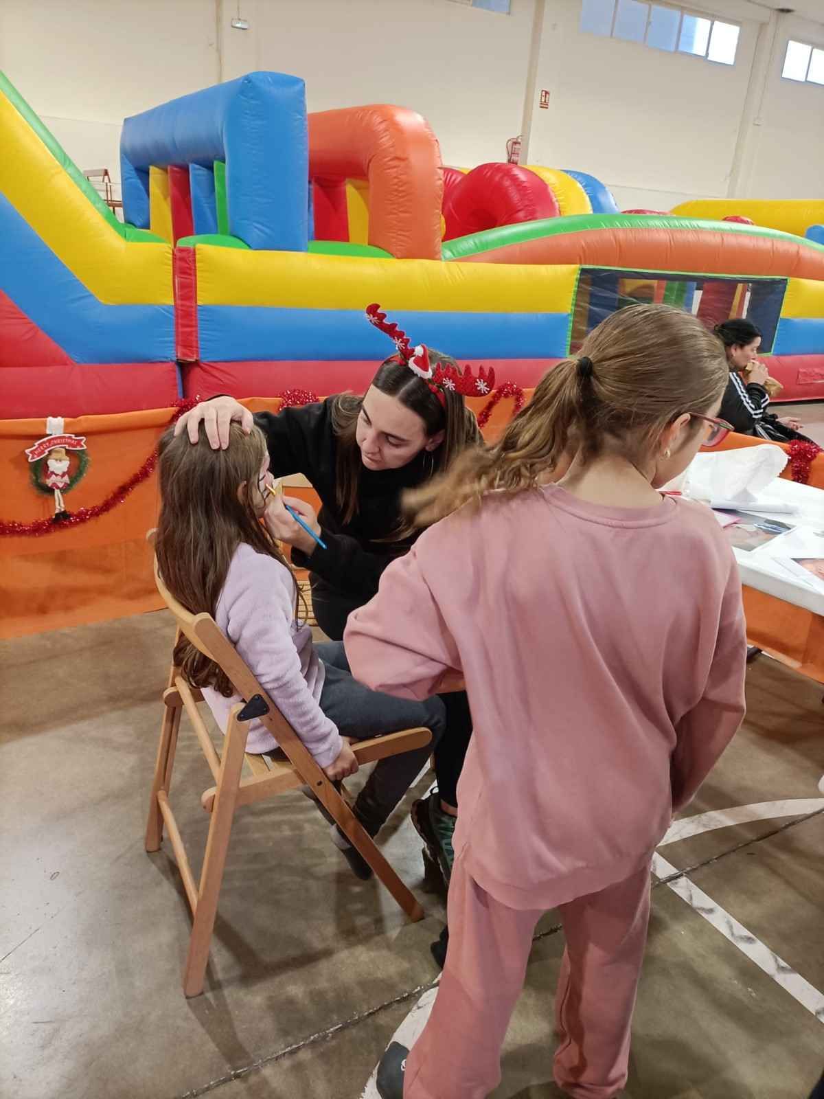 Niños jugando en un colorido castillo hinchable con un adulto dentro.