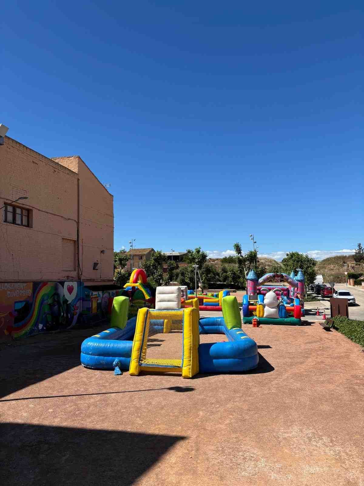 Parque infantil al aire libre con coloridas estructuras hinchables para saltar bajo un cielo azul despejado.