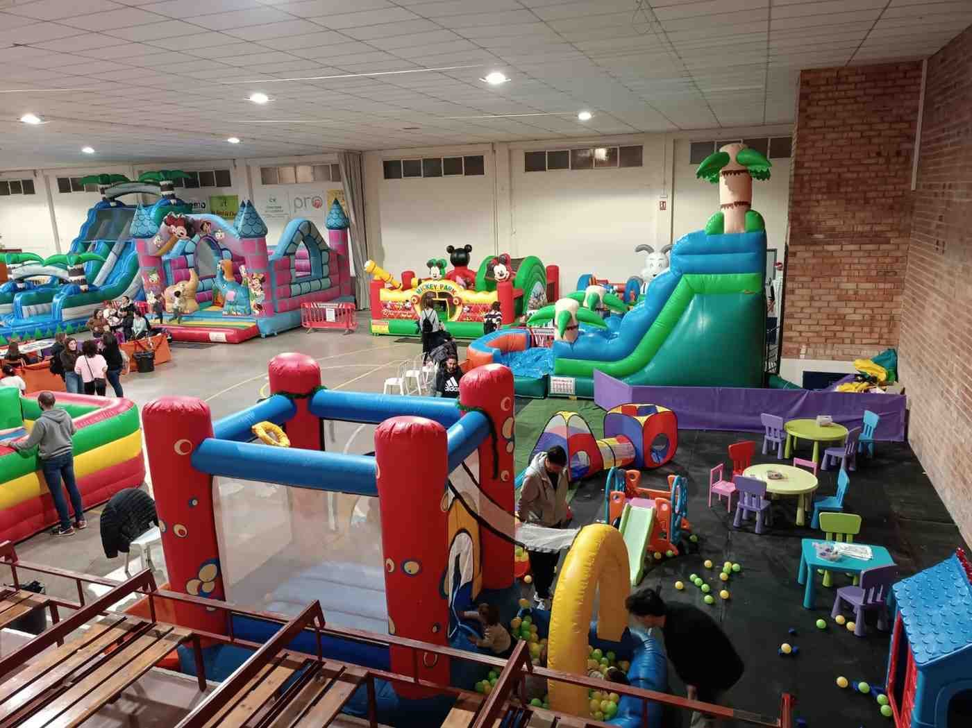 Sala de juegos cubierta con coloridas estructuras de juego inflables, toboganes y circuitos de obstáculos.