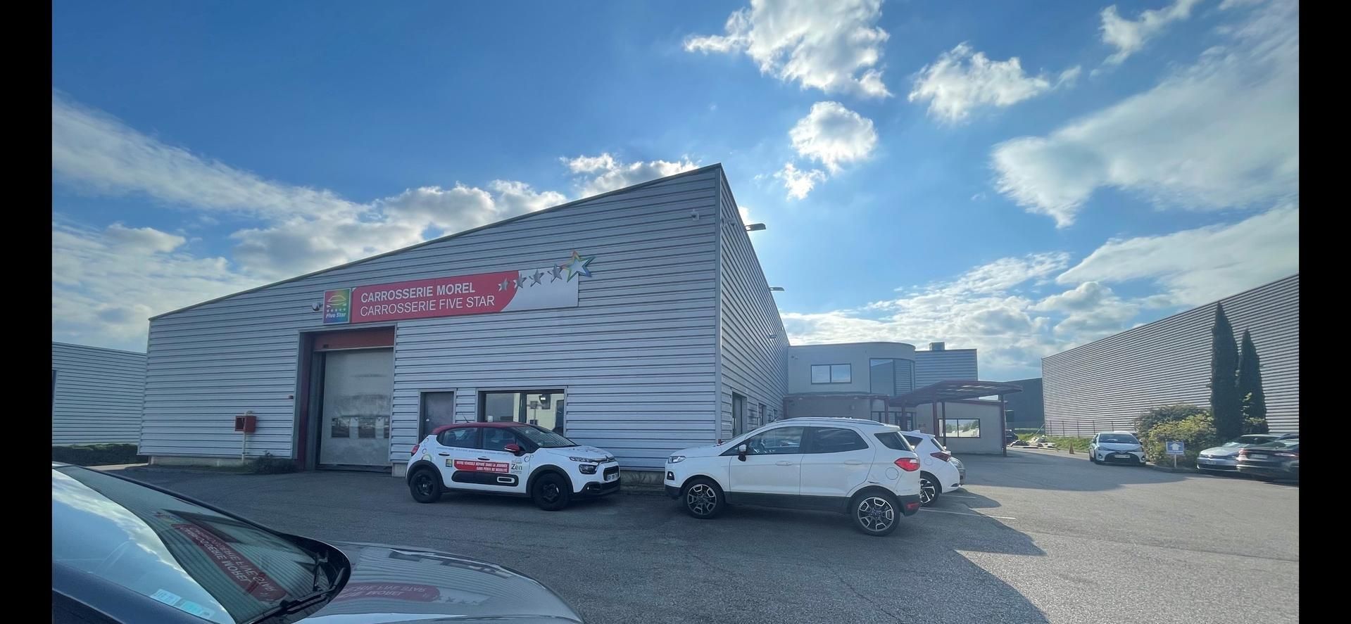 Des voitures garées devant un bâtiment, sous un ciel bleu.