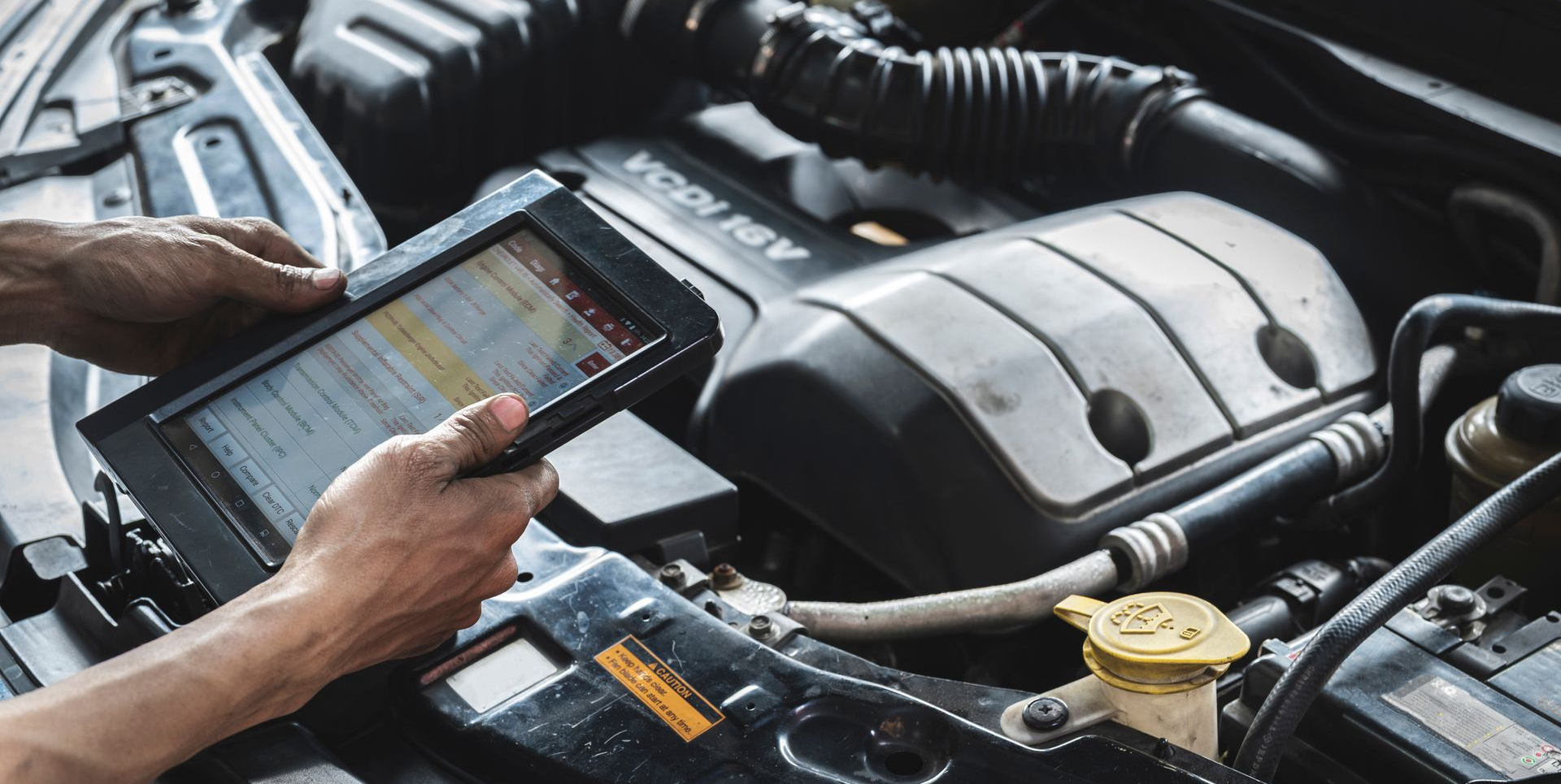 Une personne utilisant un outil de diagnostic sur un moteur de voiture.